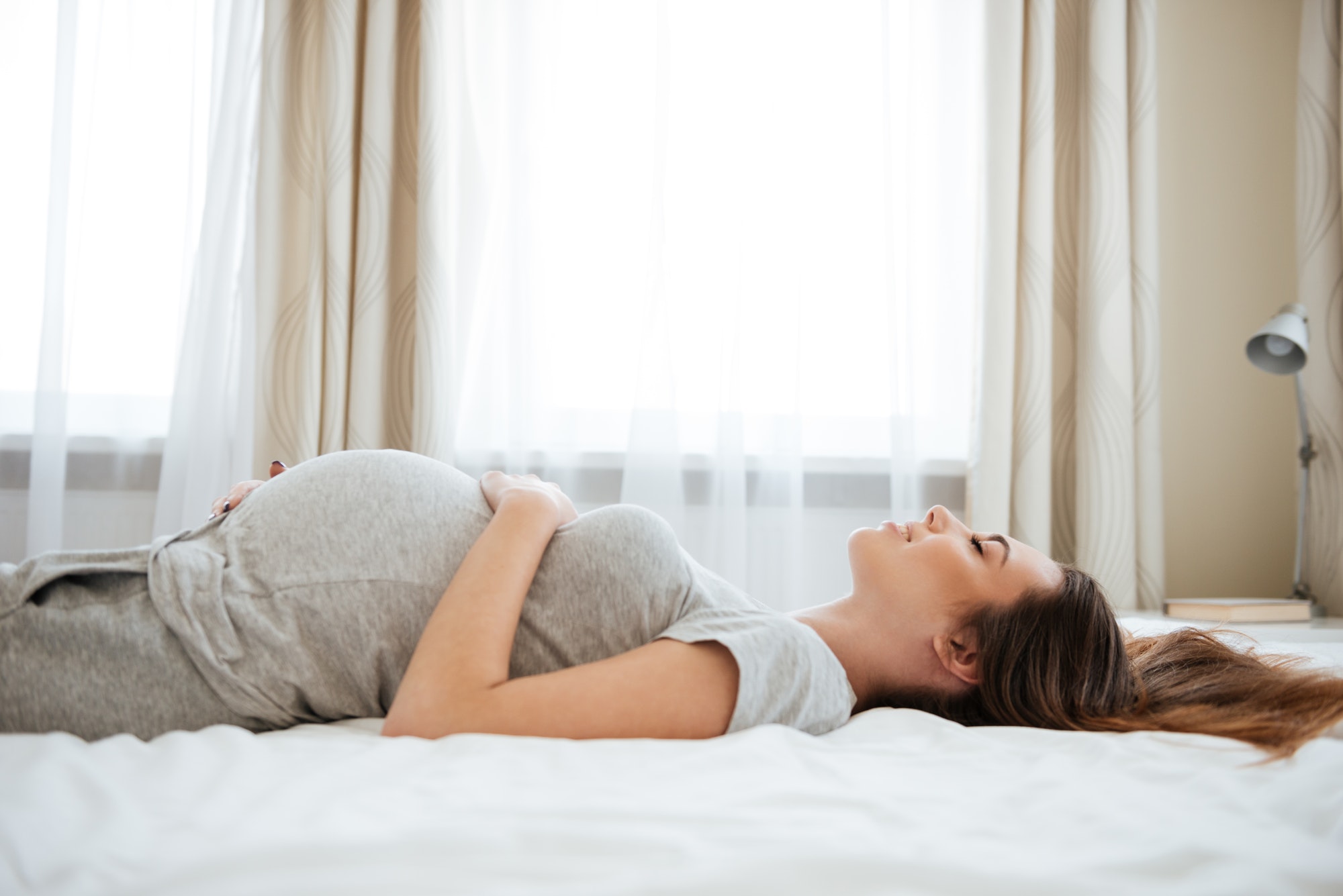 smiling pregnant young woman lying and relaxing on bed