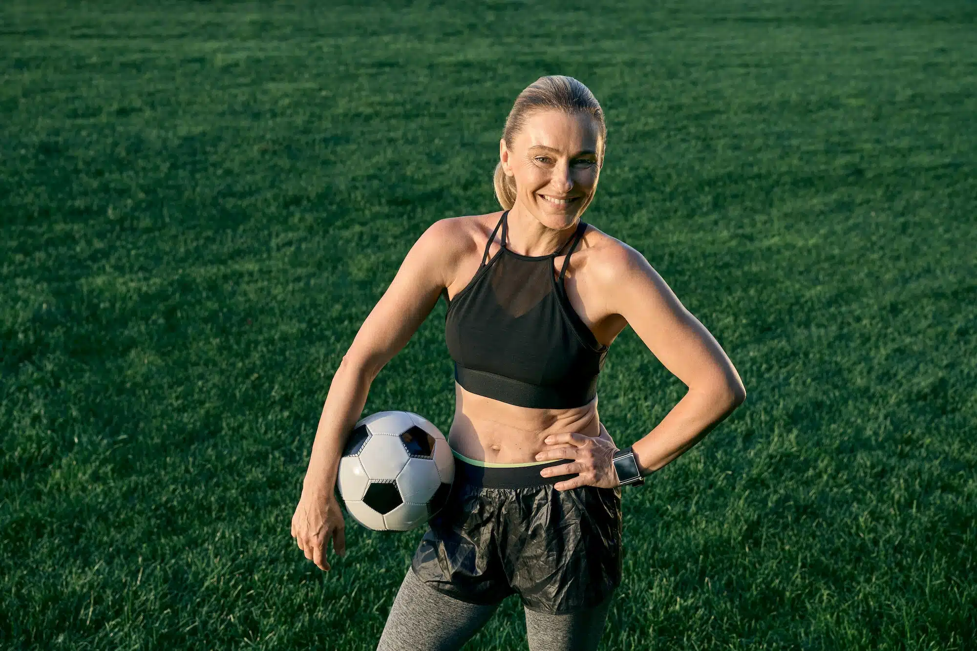 Active lifestyle. Sporty beautiful middle aged woman, football player smiling at camera and holding