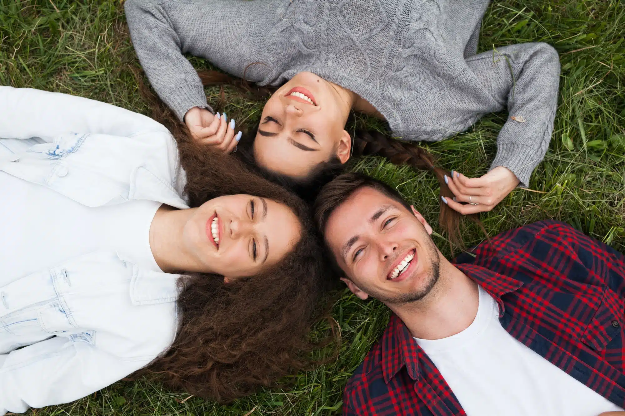 Young smiling people lying on grass